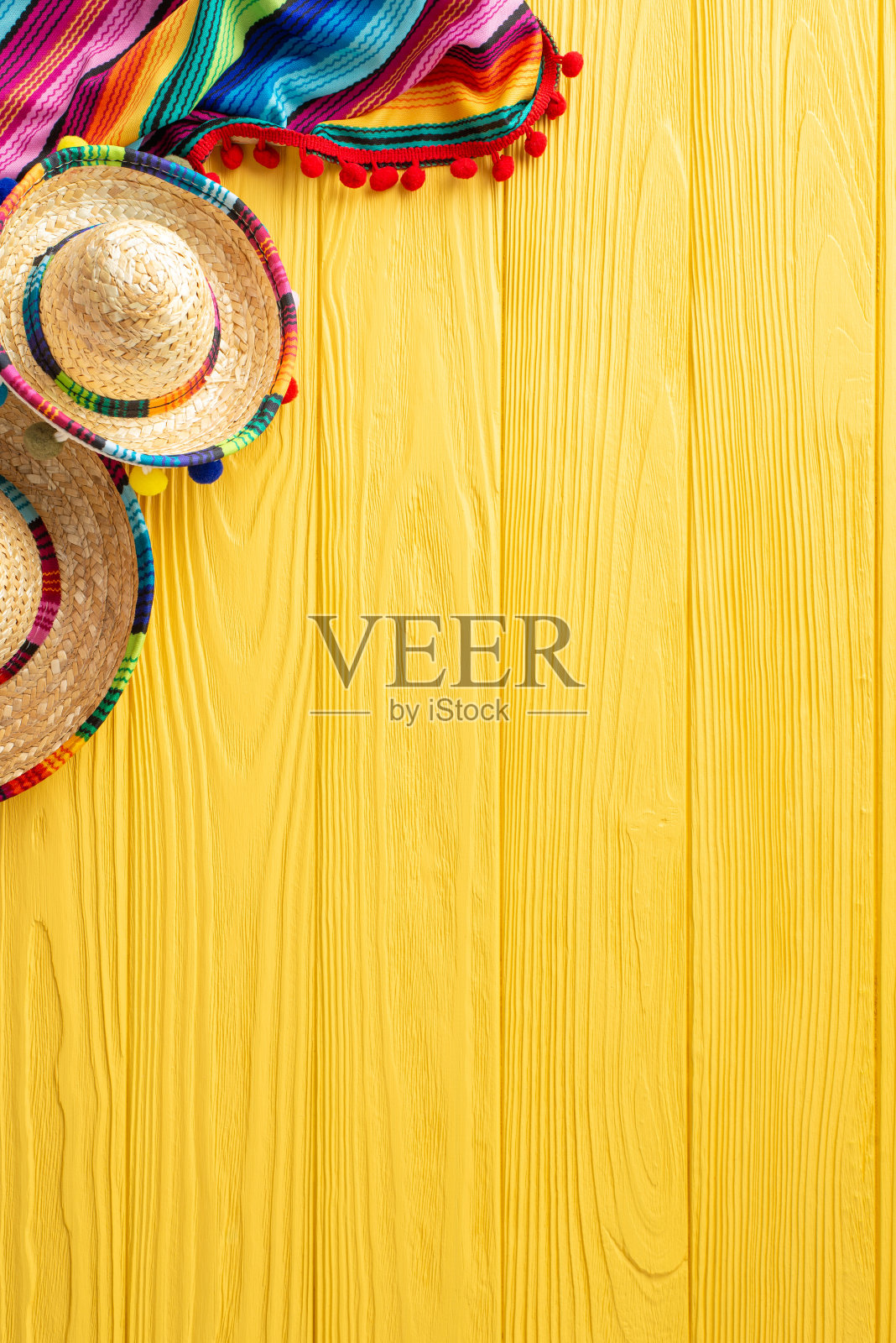 庆祝五月五日节，在一张黄色的桌子上，你可以从垂直的角度看到墨西哥宽边帽和披肩。非常适合文本或广告照片摄影图片