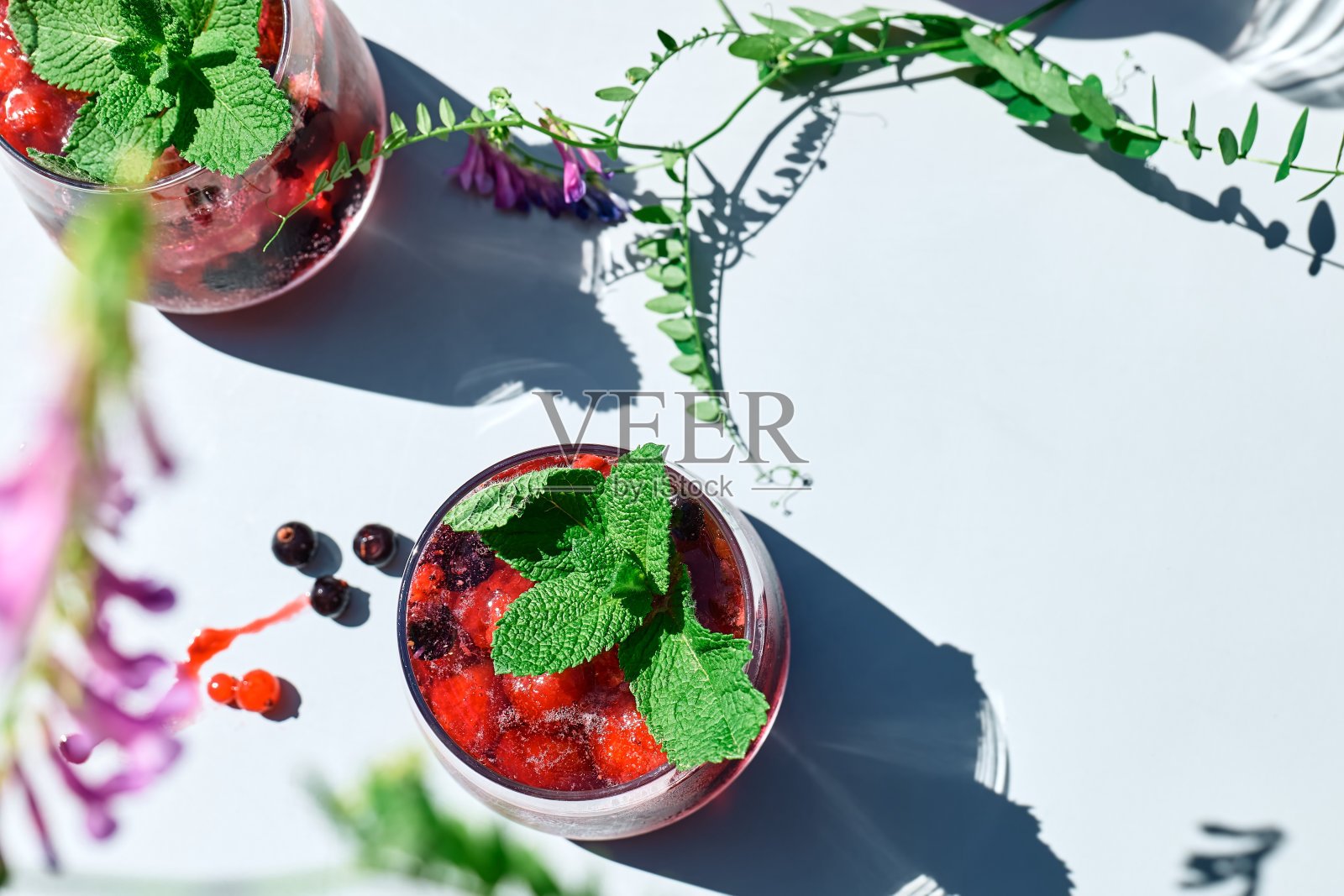 浆果清凉清凉的夏日饮品。鸡尾酒或无酒精鸡尾酒，搭配成熟的时令浆果和薄荷。排毒饮料。水果冰解渴饮料。照片摄影图片