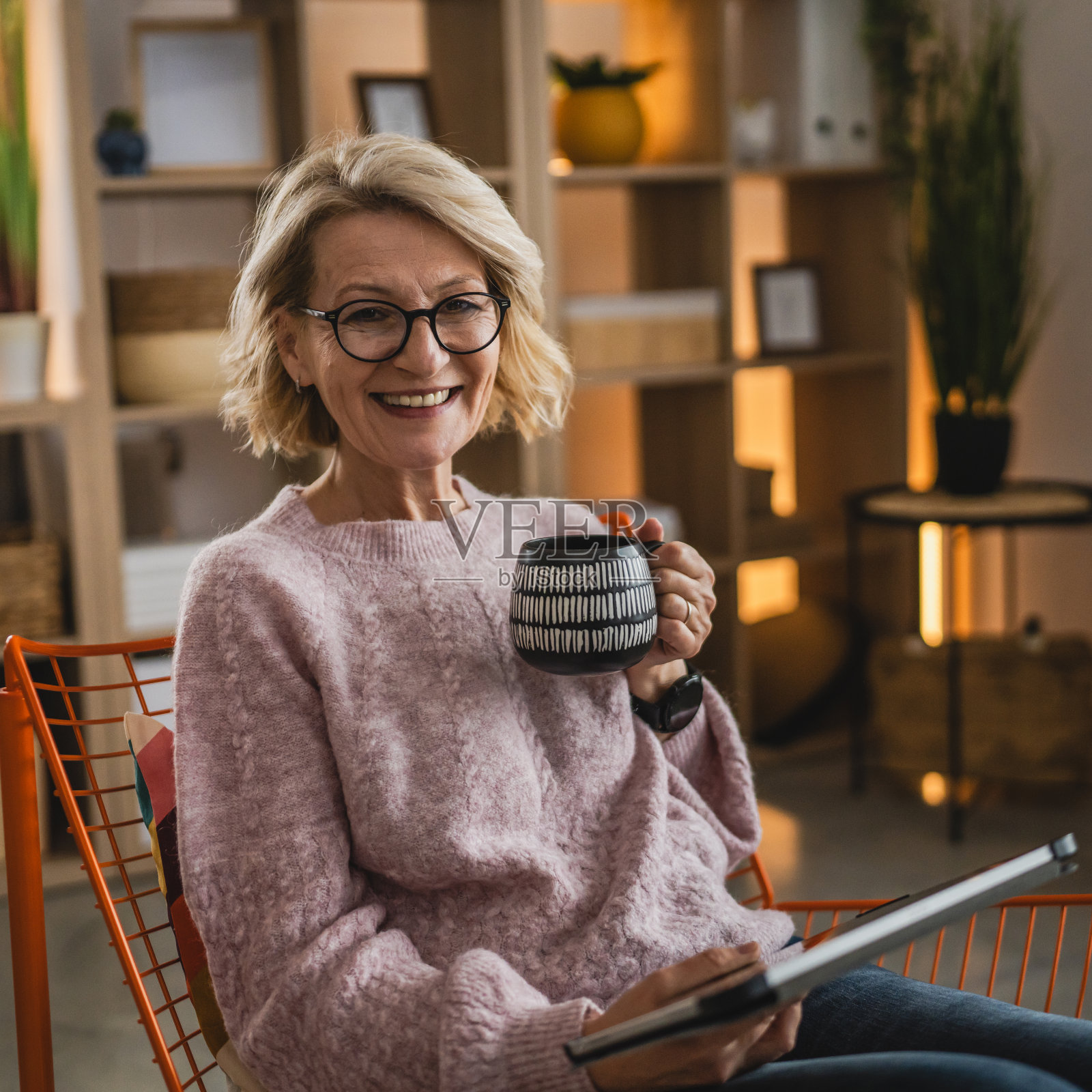 戴眼镜的成熟金发女人在家里使用数码平板电脑照片摄影图片