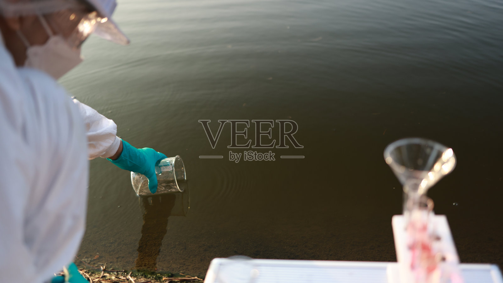 生物学家检查水样是否感染。戴着手套的手与烧杯和试管在湖，河，海的背景。污染生态、环境照片摄影图片