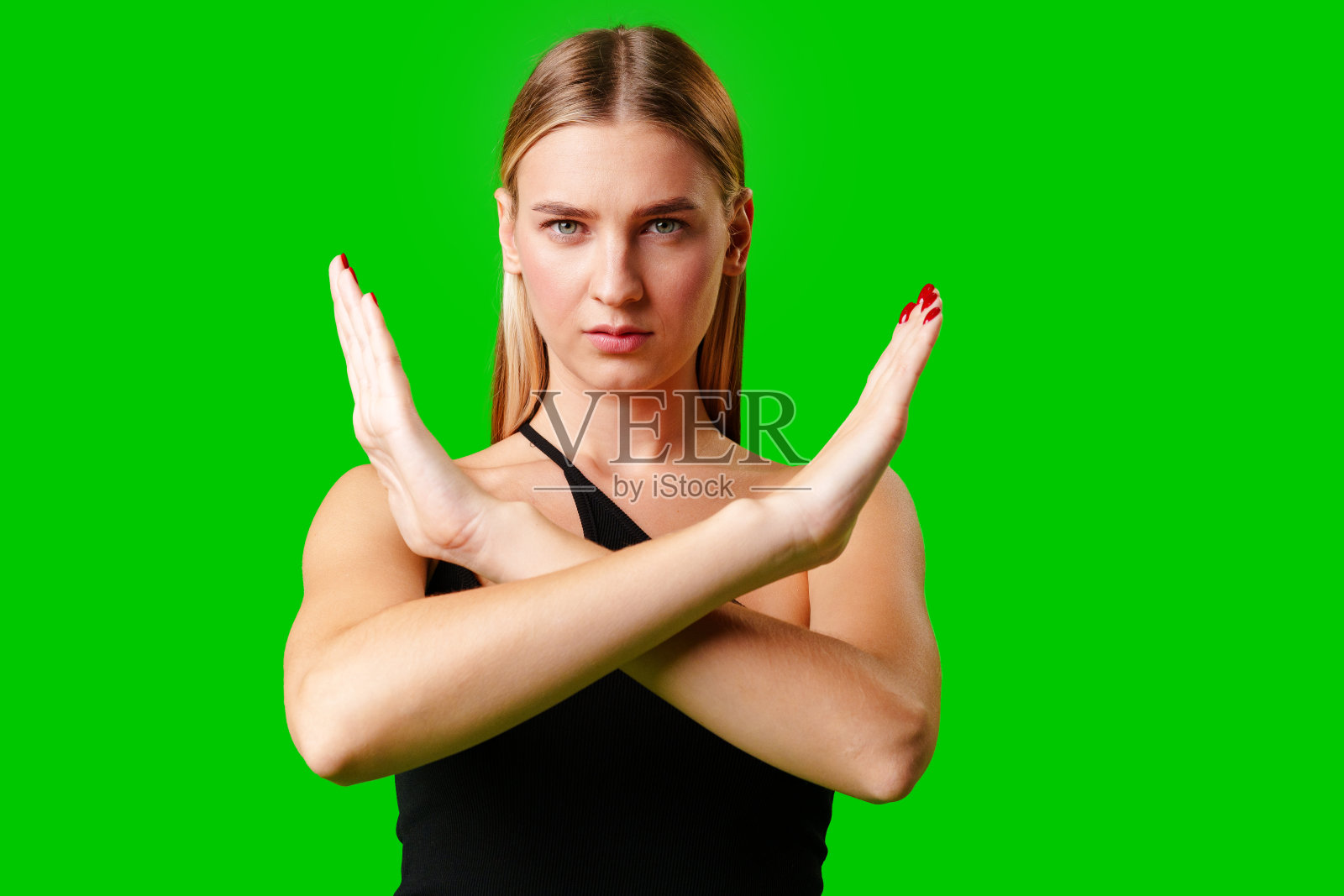 年轻女子在绿色背景上做停止手势照片摄影图片