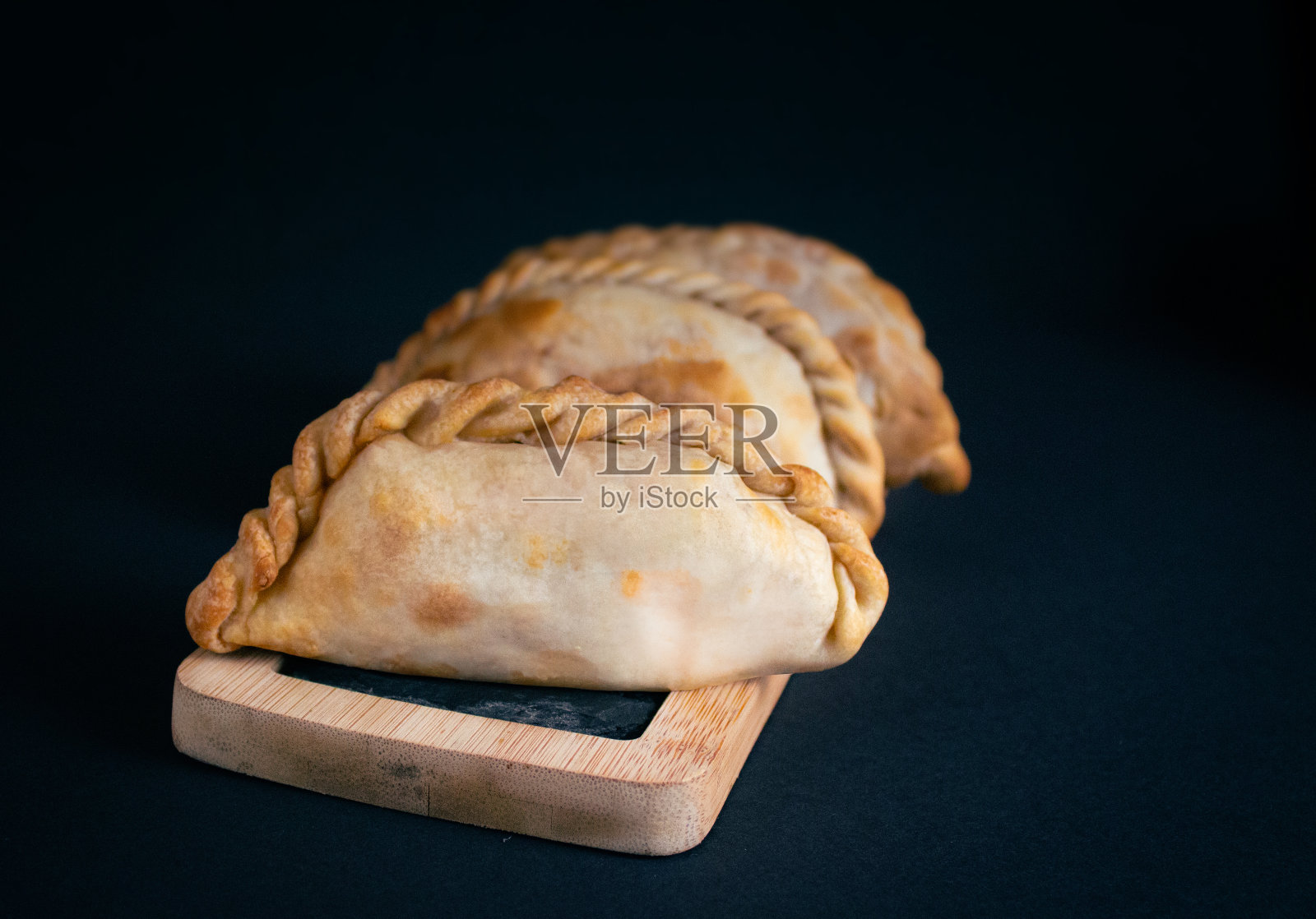 几个阿根廷肉馅卷饼在木板和黑色石板，黑色背景，餐厅的照片照片摄影图片