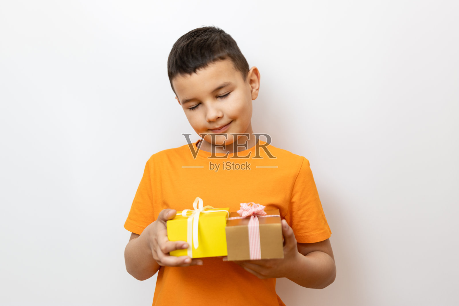 男孩因为收到礼物而闭上了眼睛。真诚的孩子的情感。照片摄影图片