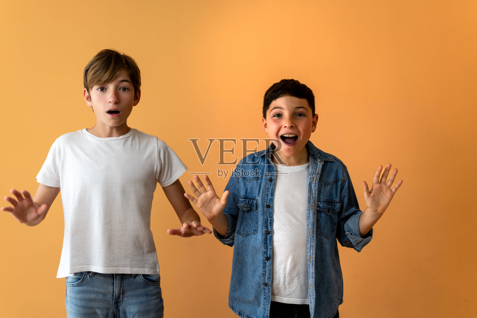 两个孩子，举起双手，露出惊讶的表情。照片摄影图片