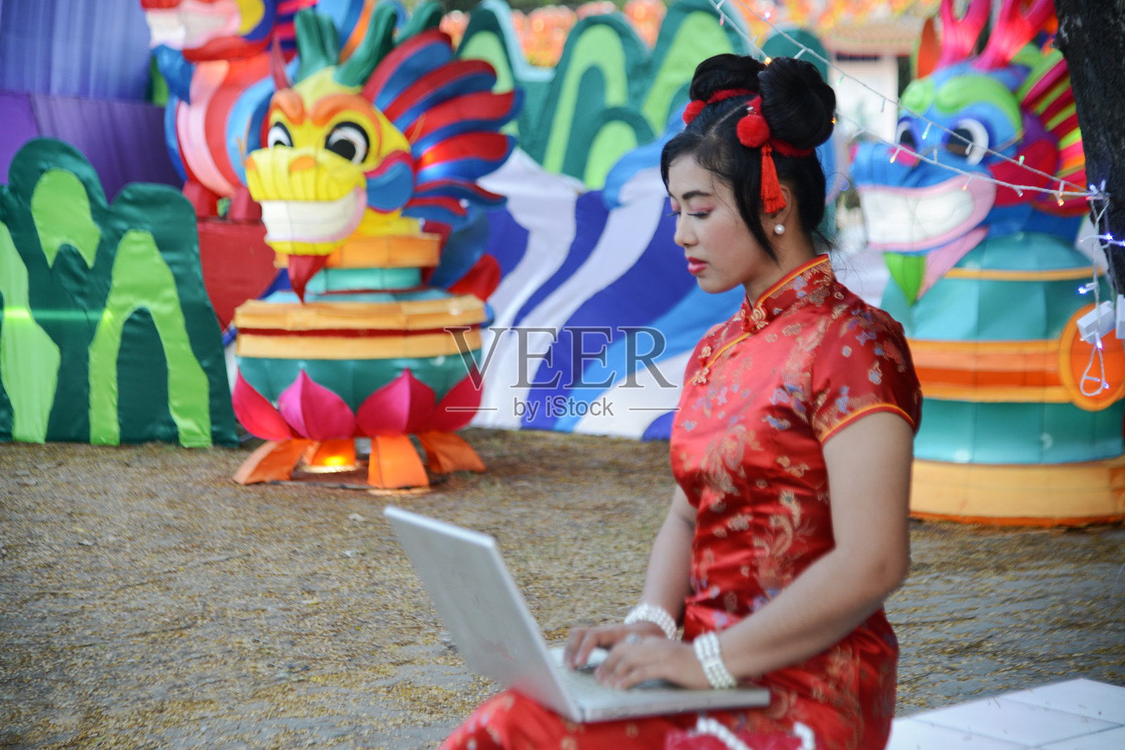 漂亮的亚洲女人拿着笔记本电脑，身后有个灯笼木偶。照片摄影图片