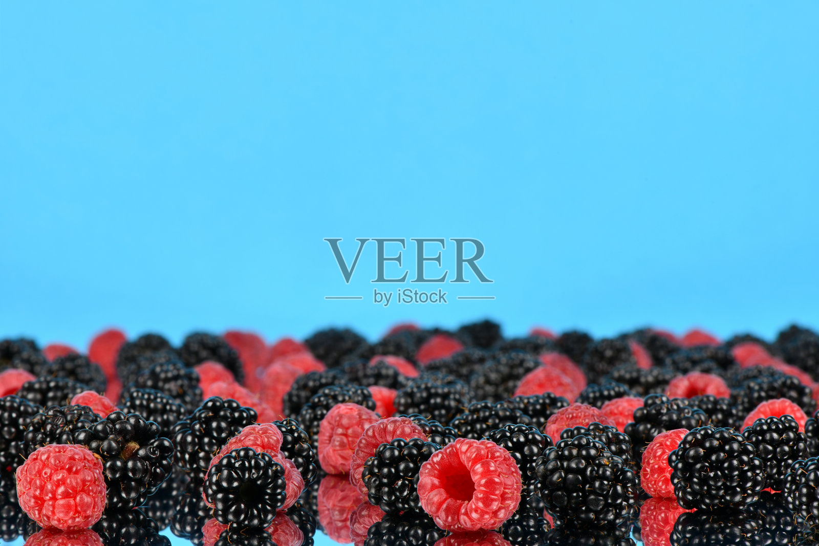 浅蓝色镜面上的覆盆子和黑莓。侧视图。高分辨率照片。有选择性的重点。照片摄影图片