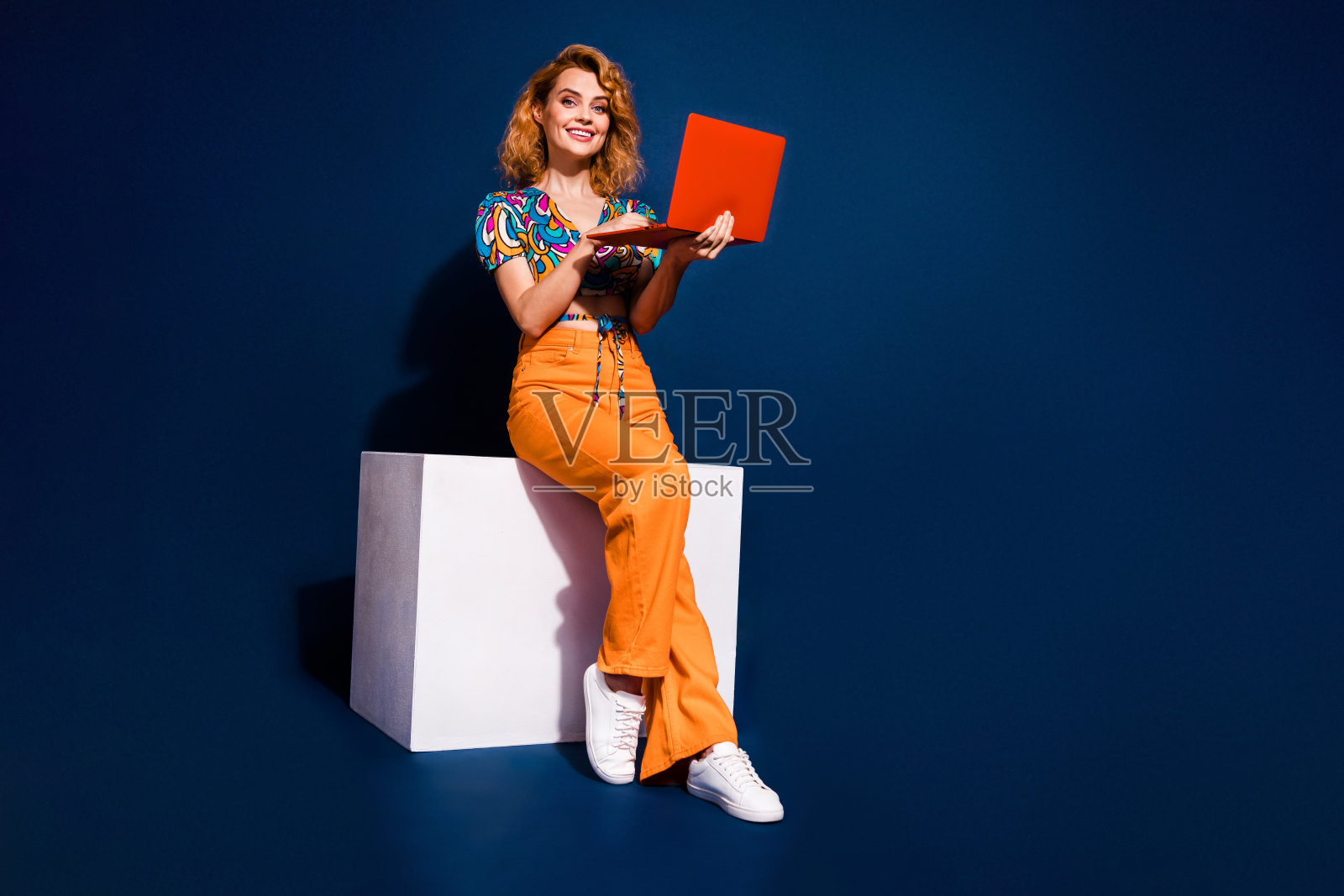 漂亮的年轻女士的全身肖像使用笔记本电脑空的空间穿上衣孤立在深蓝色的背景照片摄影图片