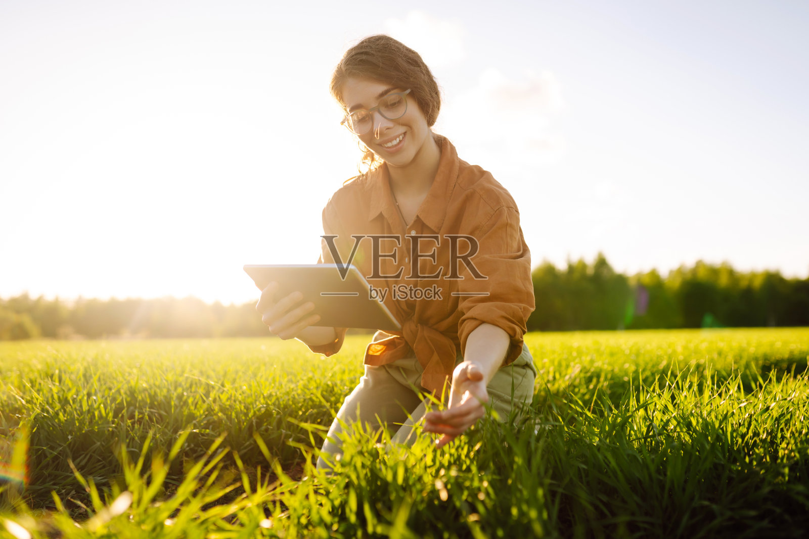 一位农妇走在她种在地里的植物的绿芽之间。照片摄影图片