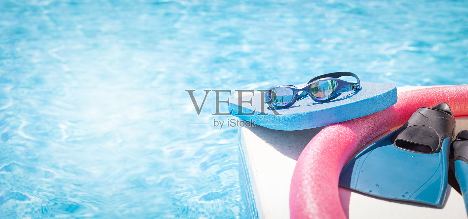 泳池附近备有运动护目镜、泳池板、游泳面和游泳用脚蹼。照片摄影图片