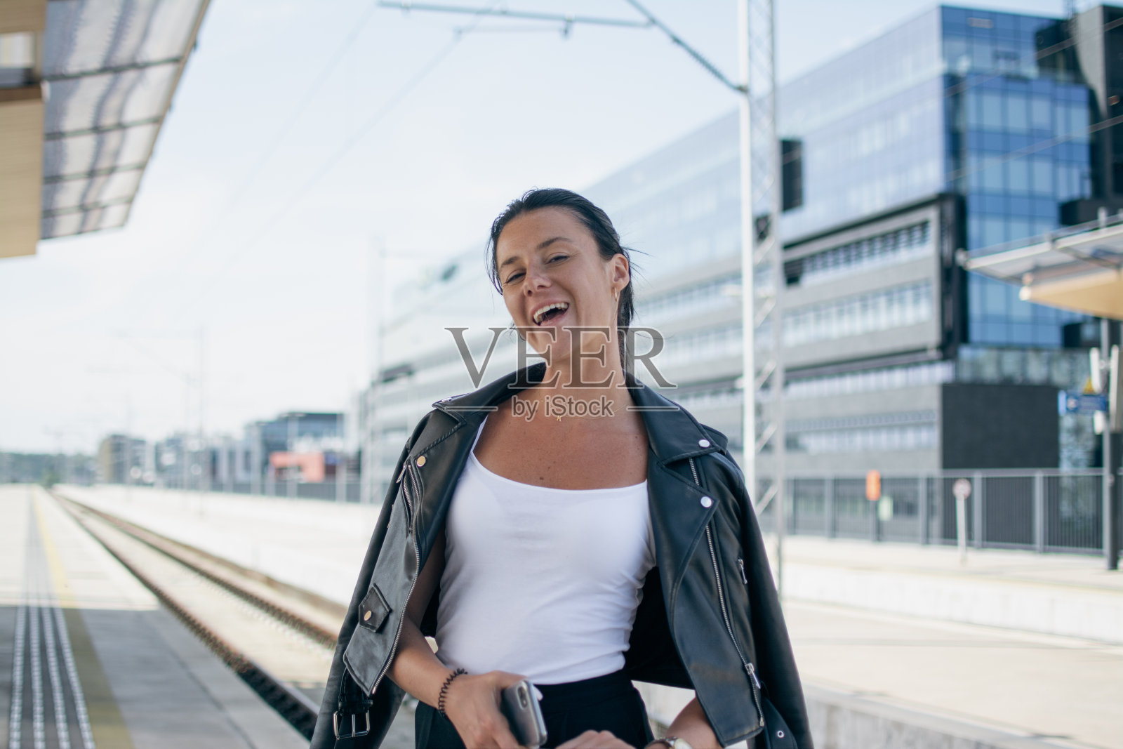 一个欢快的棕色皮肤的女孩等待火车旅行的肖像照片摄影图片