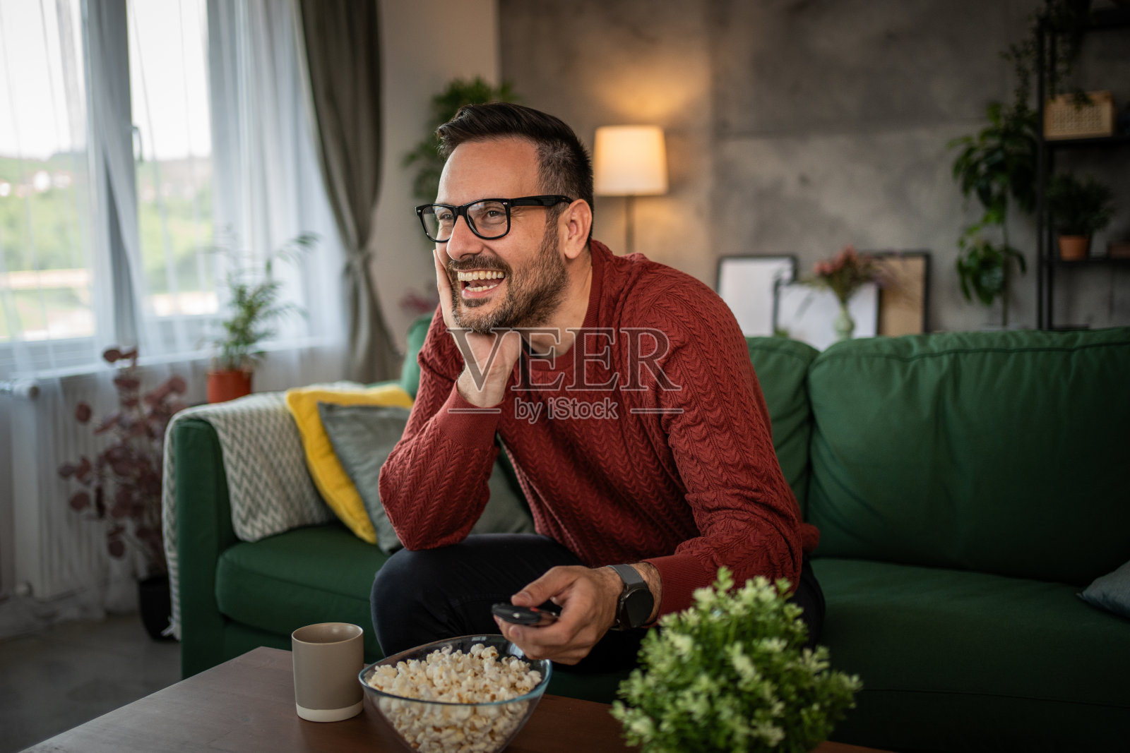 一个男人舒服地坐在沙发上看电视照片摄影图片