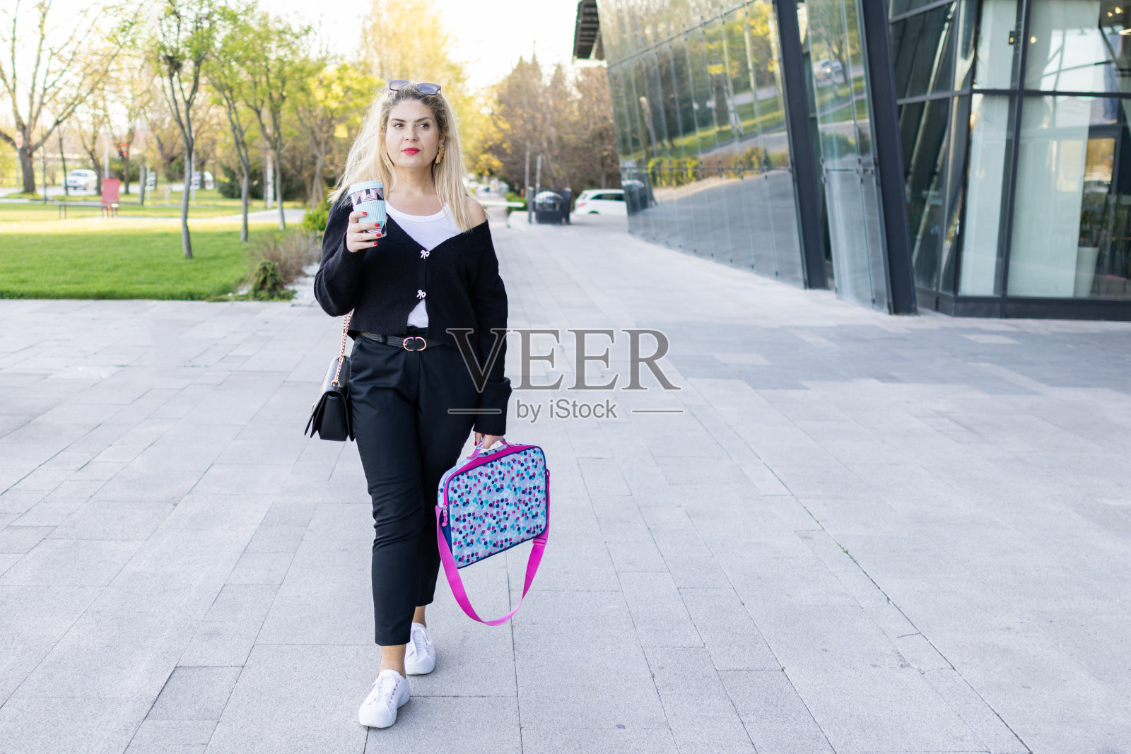 在漫长的工作日结束后，美丽微笑的商务女性通勤者在下班途中享受一杯咖啡。照片摄影图片