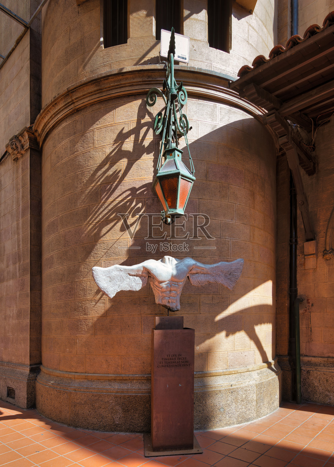 在帕多瓦圣安东尼教堂的庭院里，悬挂着一盏灯笼，上面雕刻着一只飞翔的鸽子照片摄影图片