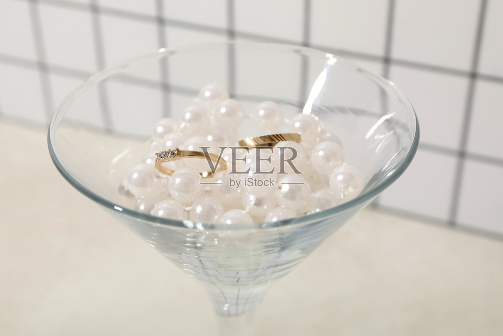 金婚戒装在玻璃杯里，配上项链。照片摄影图片