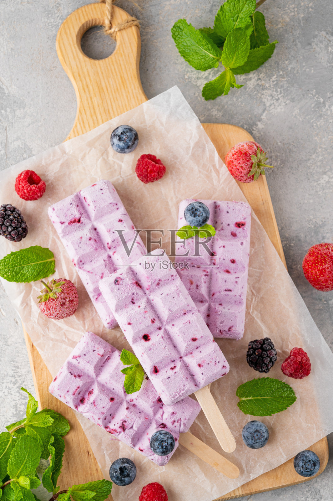 自制的浆果冰淇淋或冰棍与薄荷叶在灰色的混凝土背景。美味的夏日甜点，俯视图。照片摄影图片