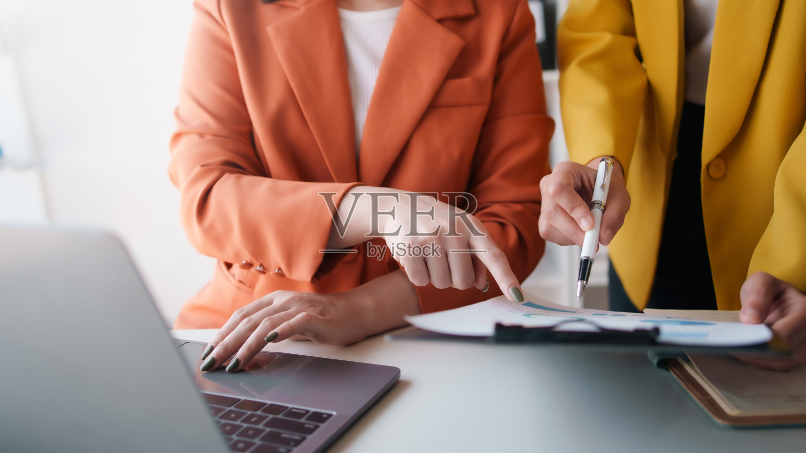 女商人指着图表开会。在会议上一起讨论的一群商人。照片摄影图片