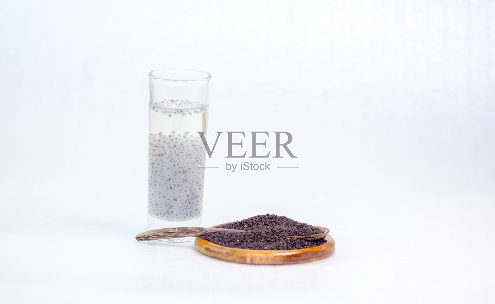 柠檬罗勒，白罗勒，柠檬罗勒，泰国柠檬罗勒放在一个平托盘里，在一个透明的玻璃杯里，白色背景上浸泡的种子和一个木勺，分开照片摄影图片