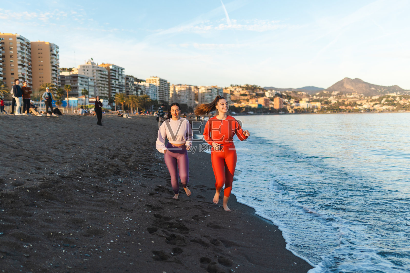 两个美丽的女人在日落时分一起在海边奔跑照片摄影图片