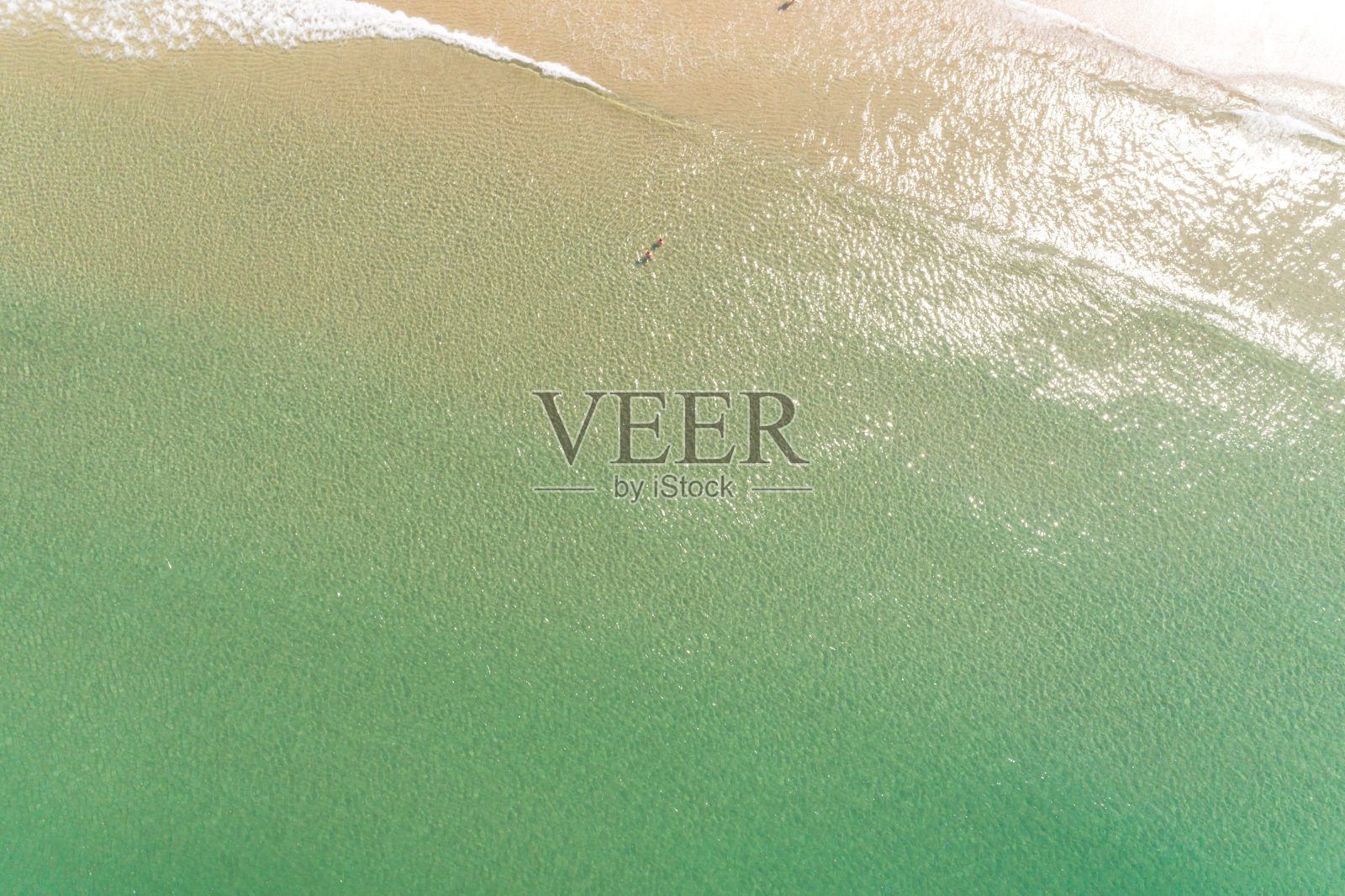 就在空中，无人机看到两个人在海滩岸边的绿松石水中享受夏天照片摄影图片