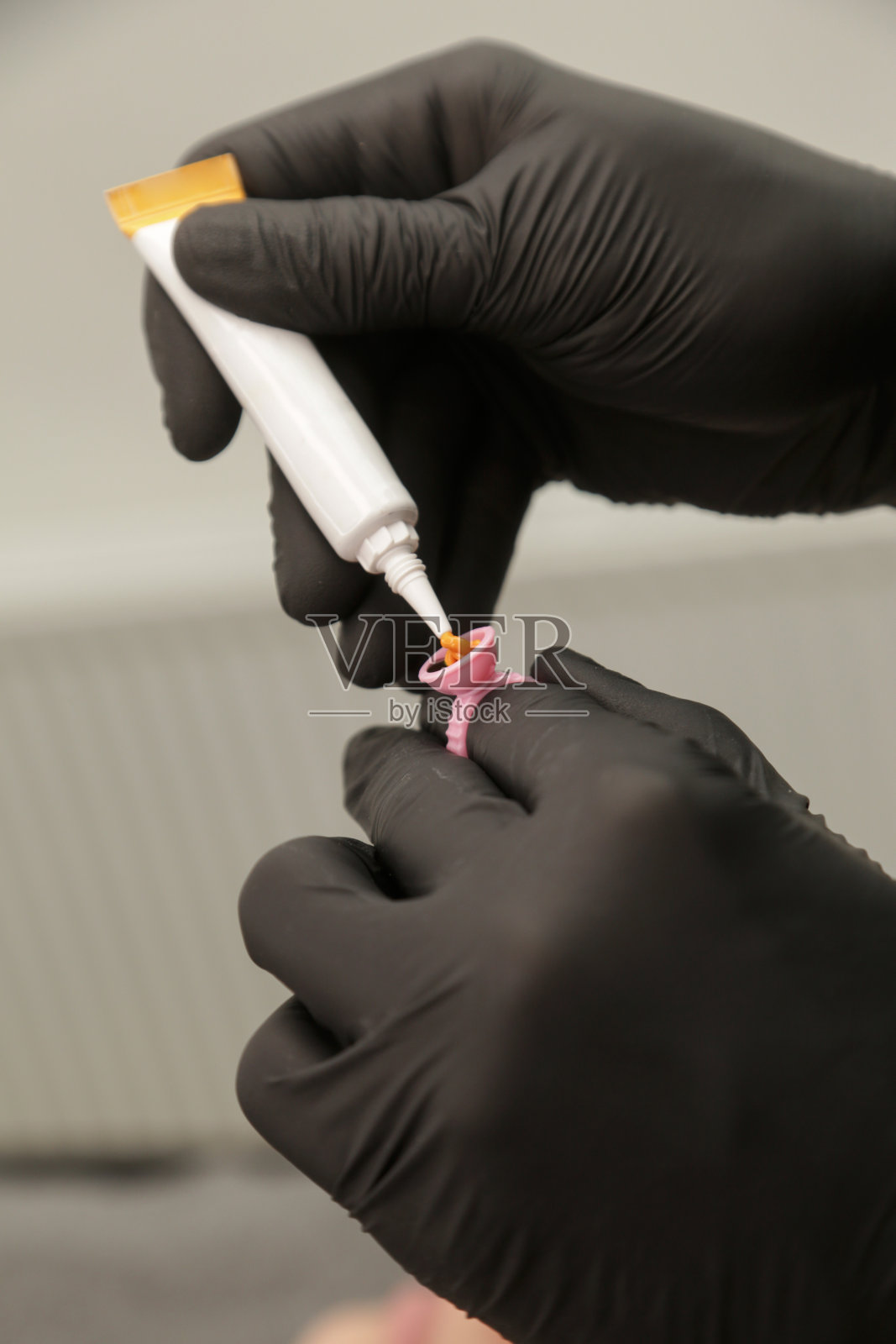 戴着黑色手套的微叶片艺术家在墨水环杯中混合颜料。眉纹颜料环容器和墨水的特写。美容手术准备。照片摄影图片