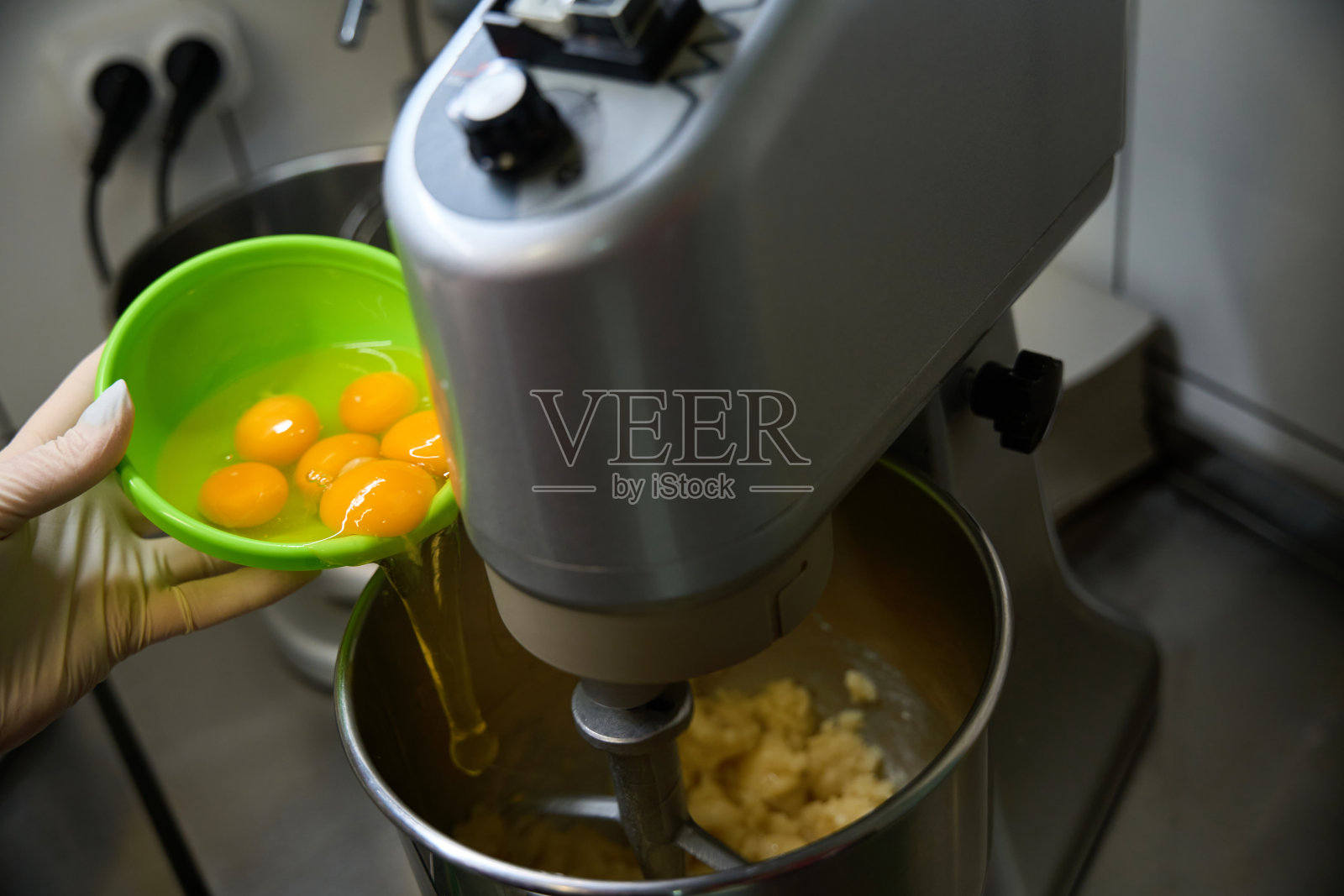 女糖果师往厨房搅拌器里加入许多鸡蛋照片摄影图片