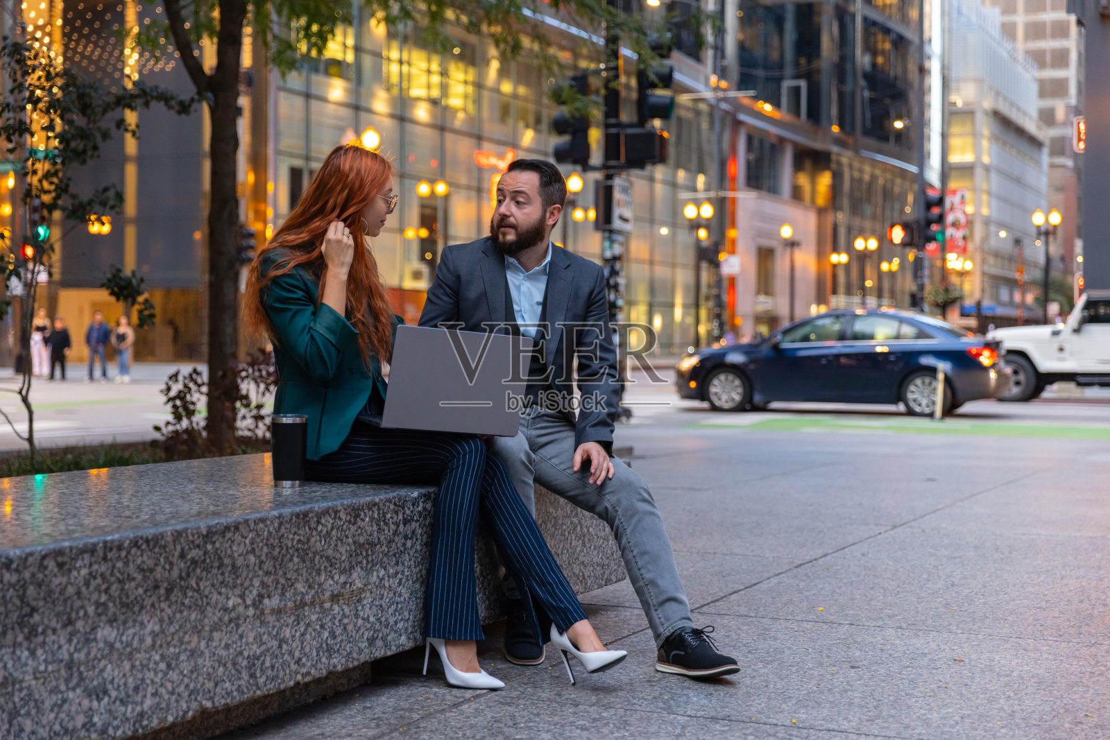 芝加哥市中心，一位红头发的女商人和她的同事正在用笔记本电脑查看工作计划照片摄影图片
