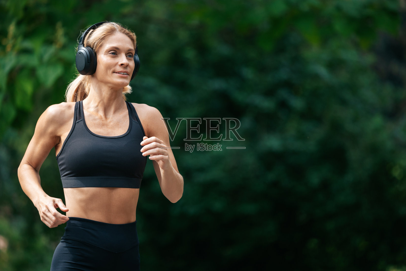 运动的金发跑步女在公园里跑步。照片摄影图片