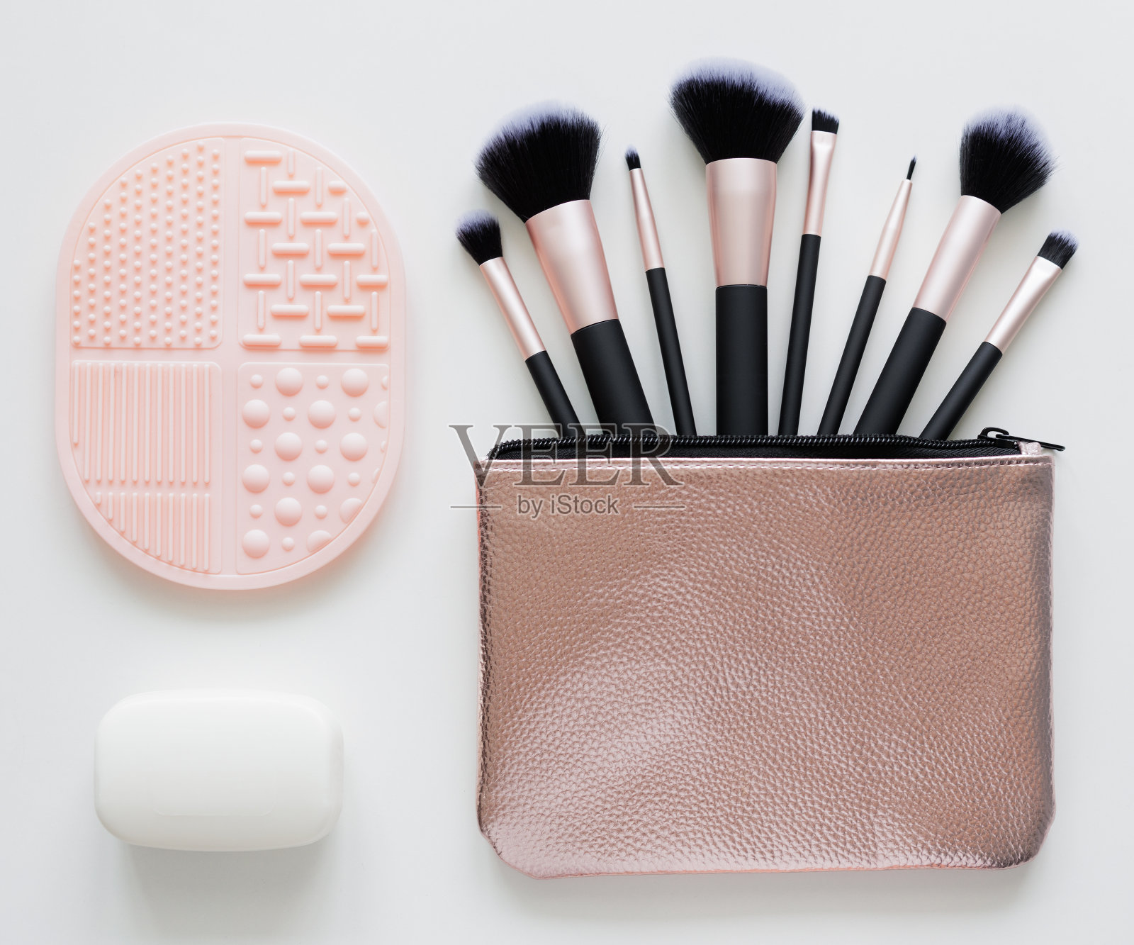 一套化妆刷在金色的情况下，肥皂和硅胶清洁剂在白色照片摄影图片