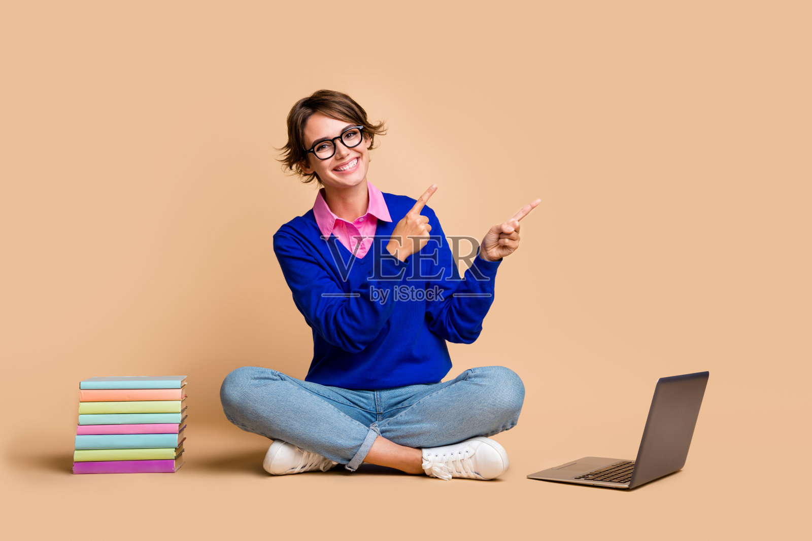 漂亮女士的全身照片坐在地板上网本直接手指空白空间提供孤立的米色背景照片摄影图片