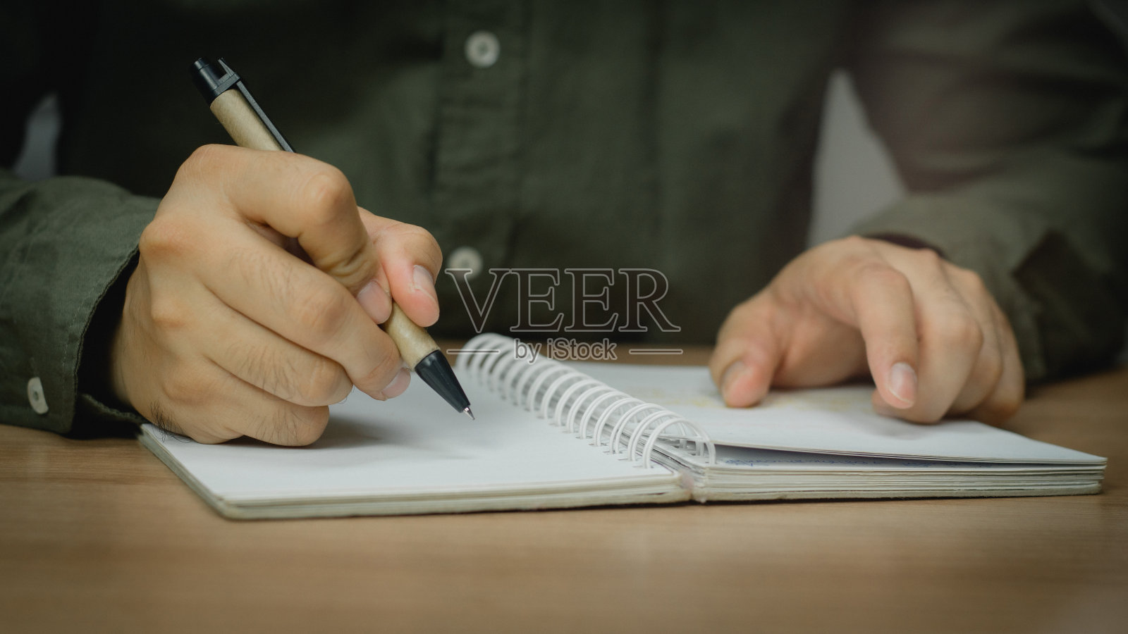 商人在工作台工作，家庭办公桌背景，清单写作策划调查热情的概念。男性的手在记事本上做笔记。照片摄影图片