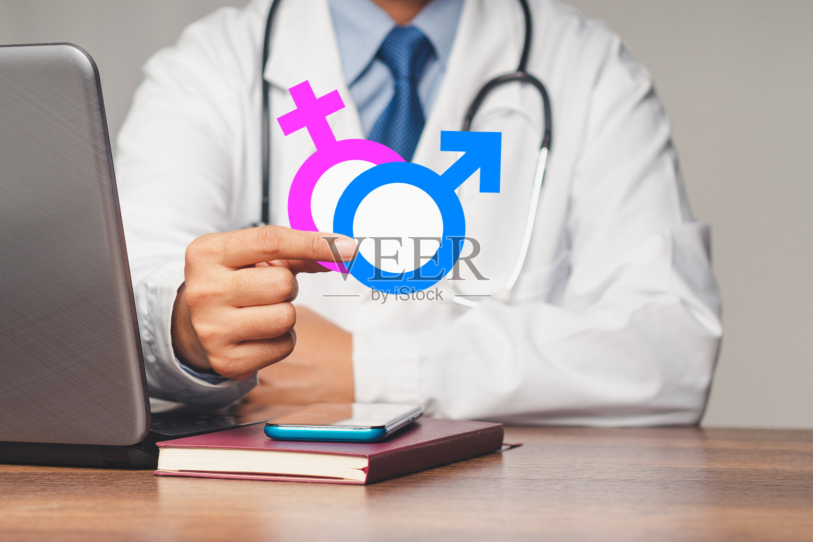 医生坐在医院里，手里拿着男性和女性的性别标志照片摄影图片