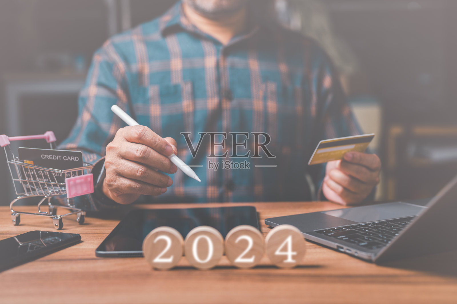 一名男子手里拿着一张信用卡，正在为即将到来的新年网购狂欢。他知道他应该存钱，但他无法抗拒犒劳自己的诱惑。照片摄影图片