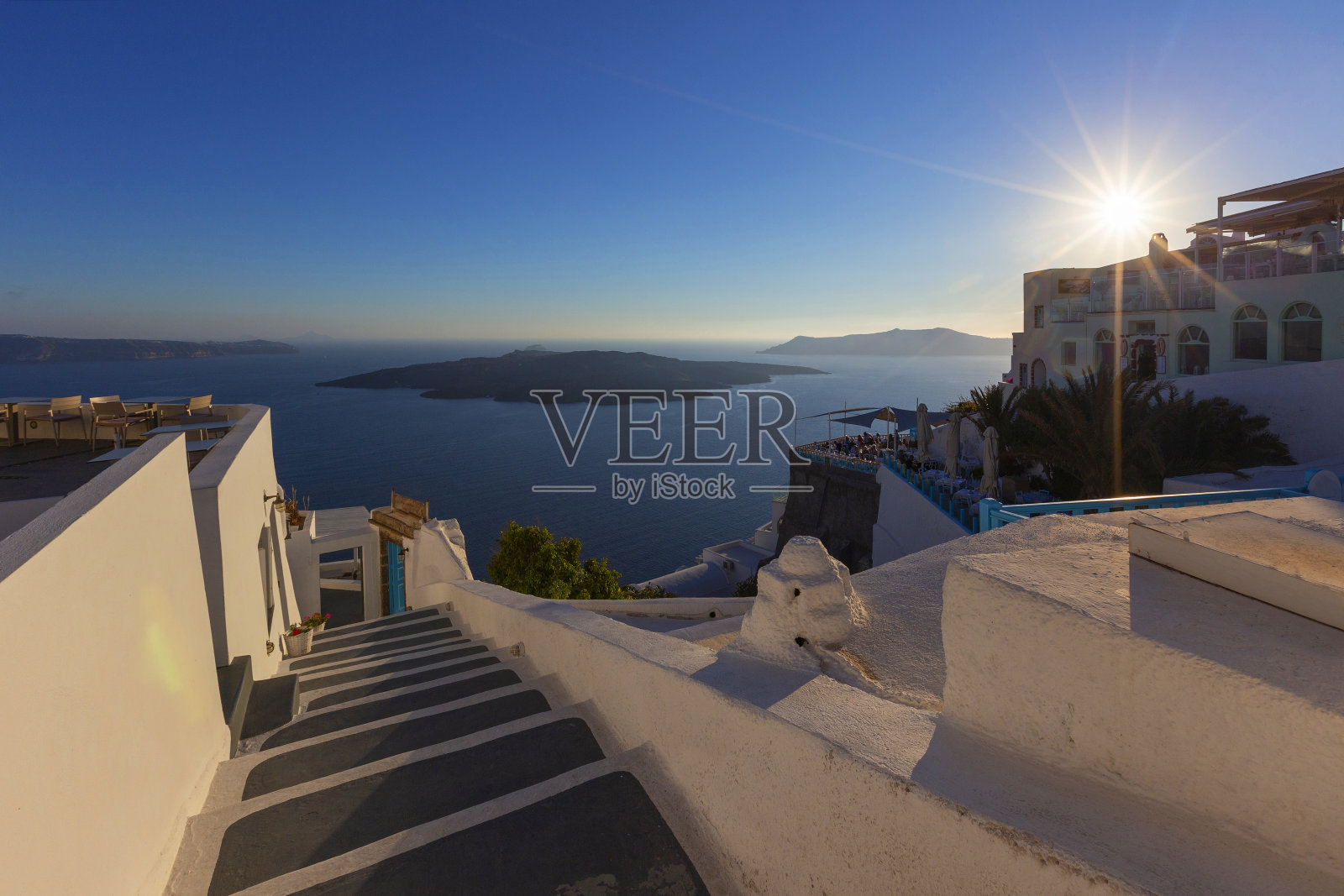 圣托里尼-风景如画的楼梯通向大海，右边的白色房子俯瞰火山口和日落时的海上岛屿。照片摄影图片