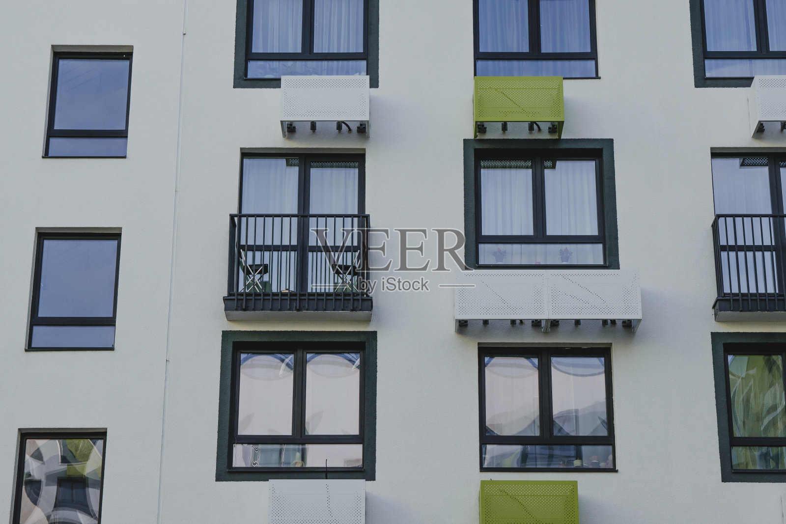 都市现代景观:一座新型现代公寓楼的多彩几何立面，窗户和空调照片摄影图片