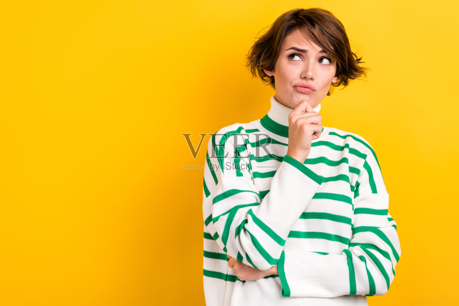 肖像可疑的工人女孩手牵着手在下巴上看空空间不确定穿条纹套头衫孤立的黄色背景照片摄影图片