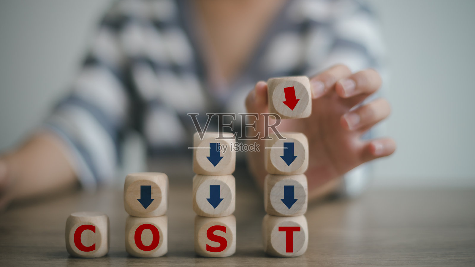 手放有成本和绿色向下箭头字样的木立方体。优化生产管理。减少公司开支以实现利润最大化。降低成本的概念。照片摄影图片