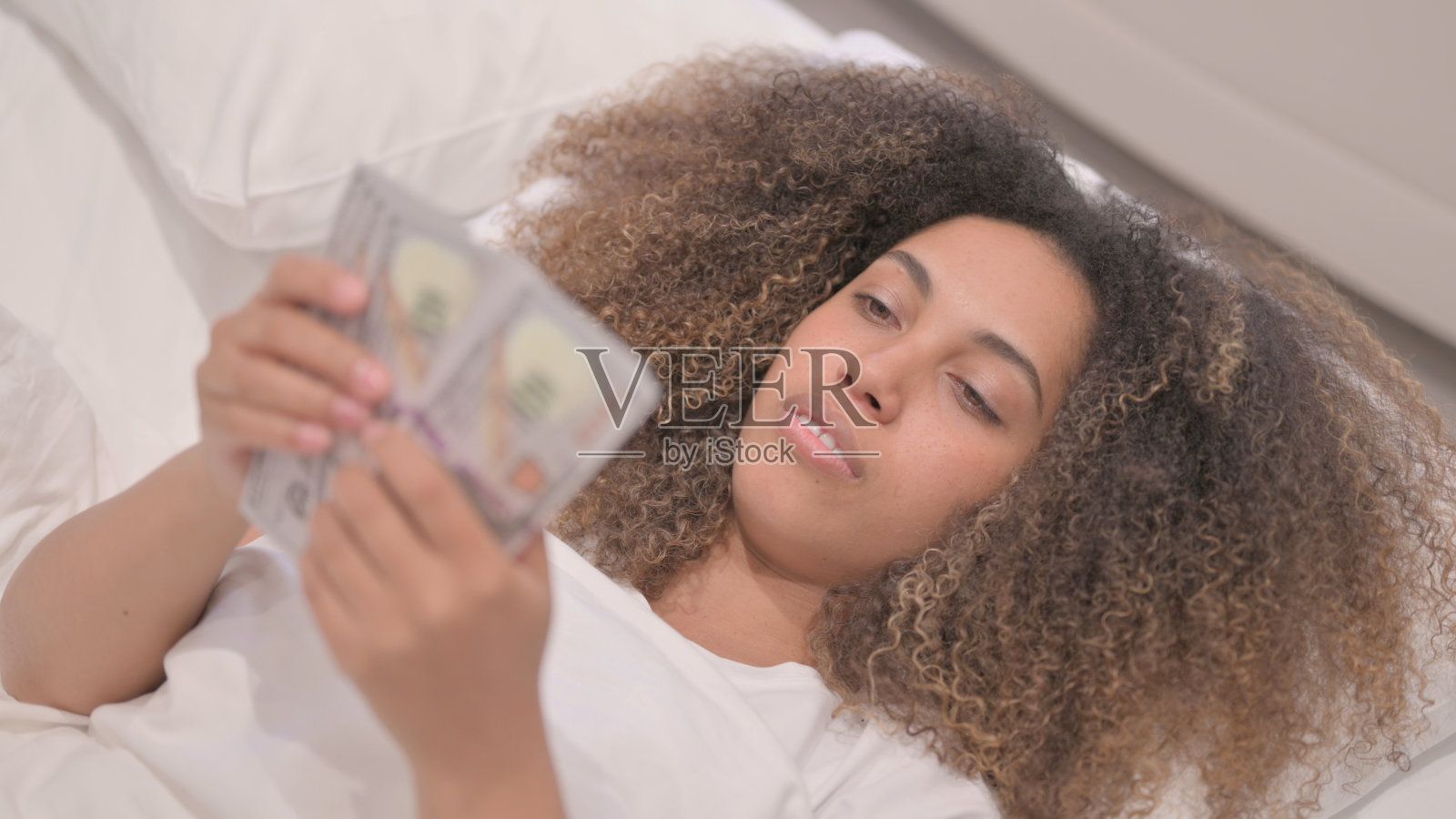 非裔美国女人在床上数钱照片摄影图片