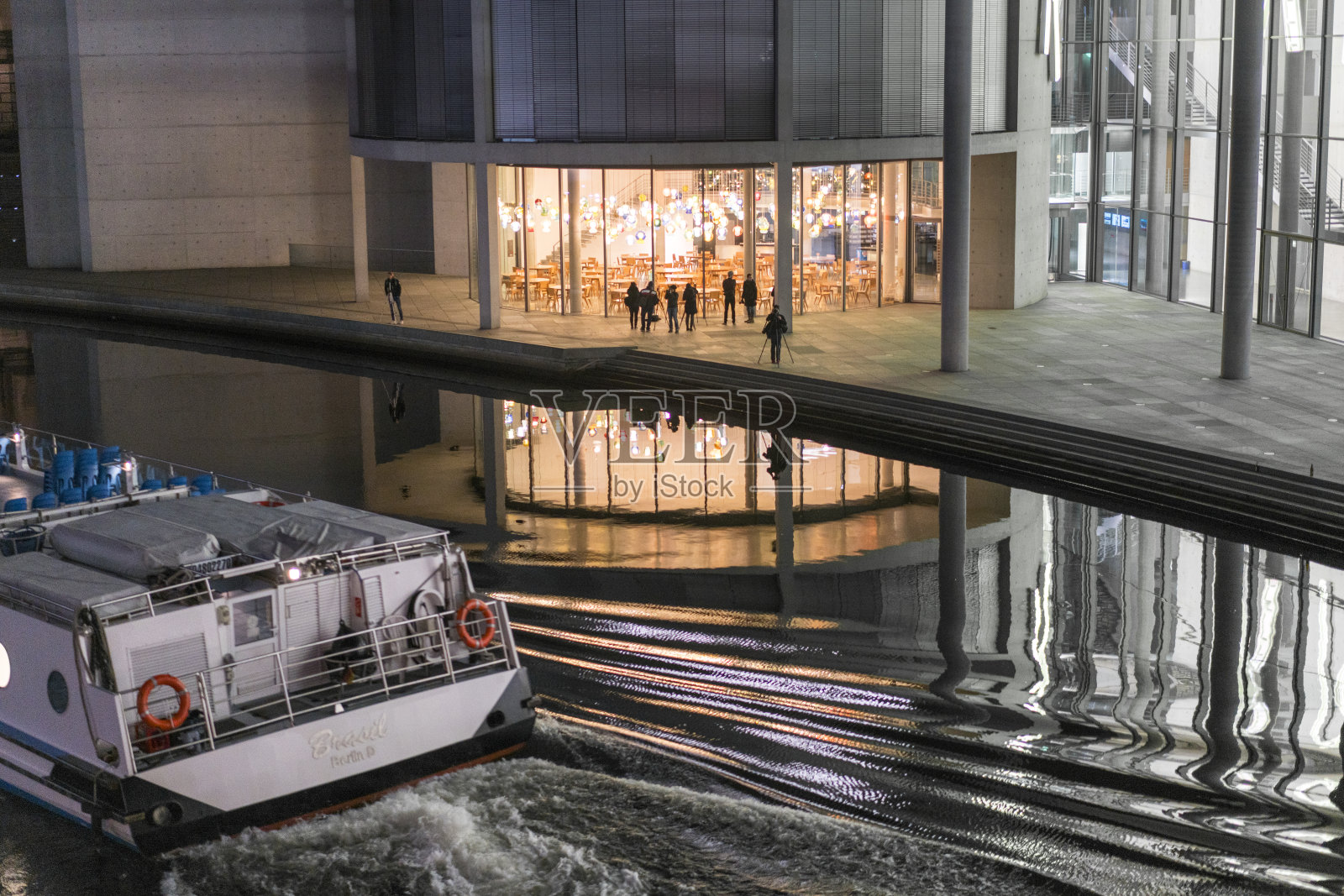 一艘游览船在施普雷河上航行，在夜晚的背景中可以看到柏林的政府区。照片摄影图片