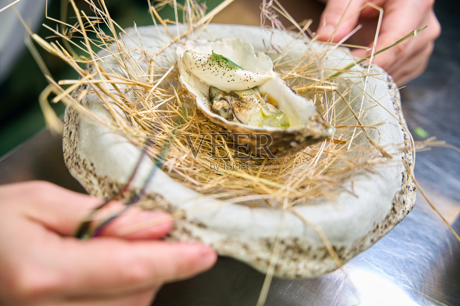 剪短头发的男厨师在鸟巢盘子里装饰牡蛎盘的特写照片摄影图片