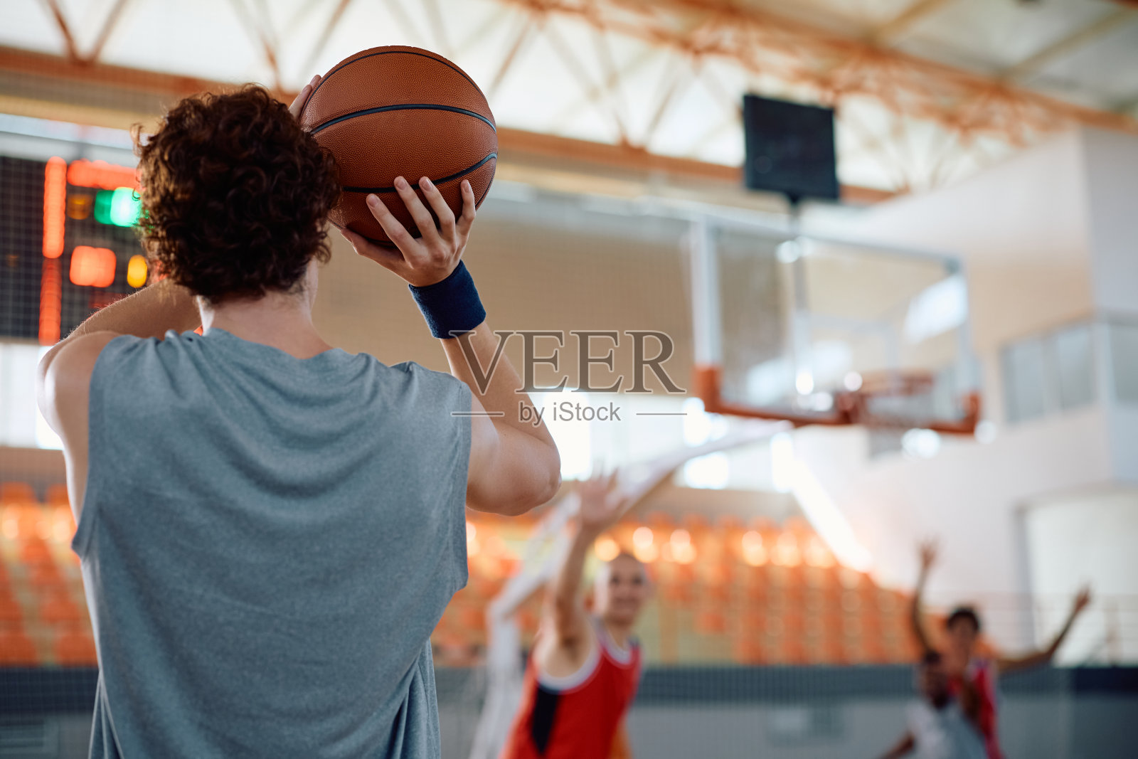 篮球运动员向篮筐投篮的后视图。照片摄影图片