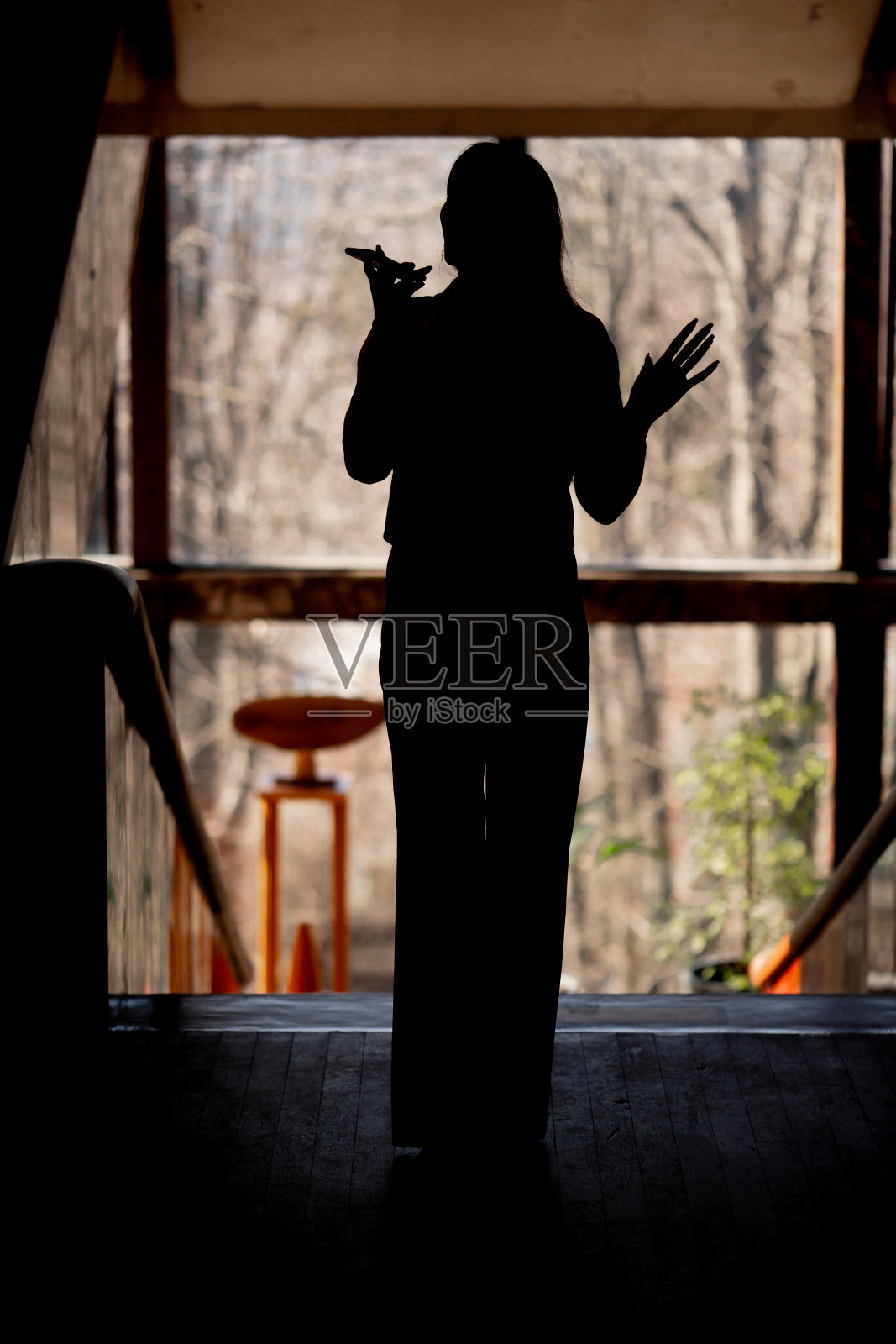 在办公室的平台上，在背光下俯瞰窗户，女孩正在打电话照片摄影图片