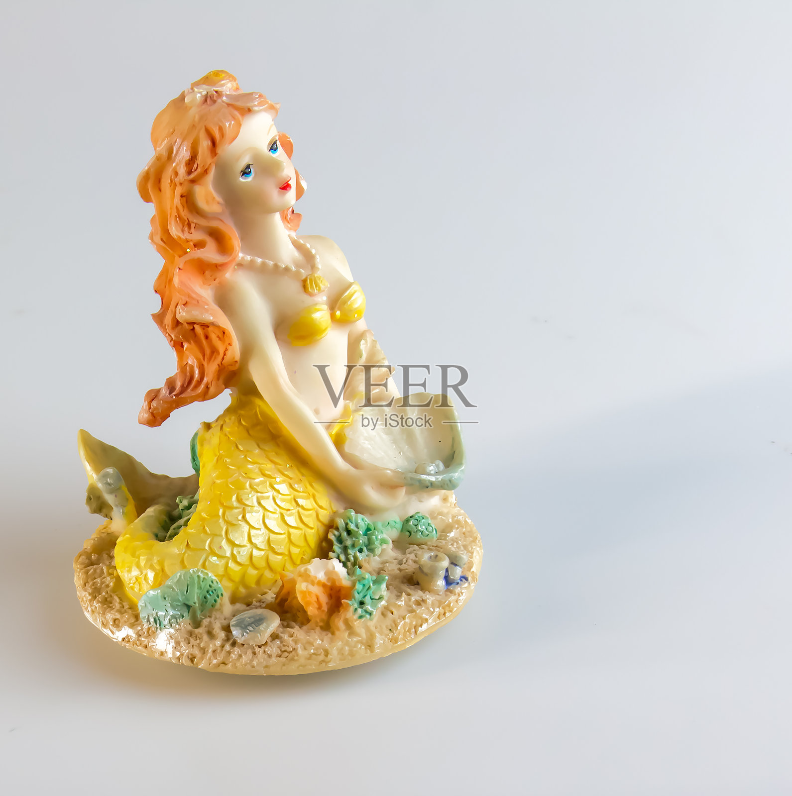 白色背景上的美人鱼雕像。童话般的性格。玩具美人鱼。女性的外表照片摄影图片