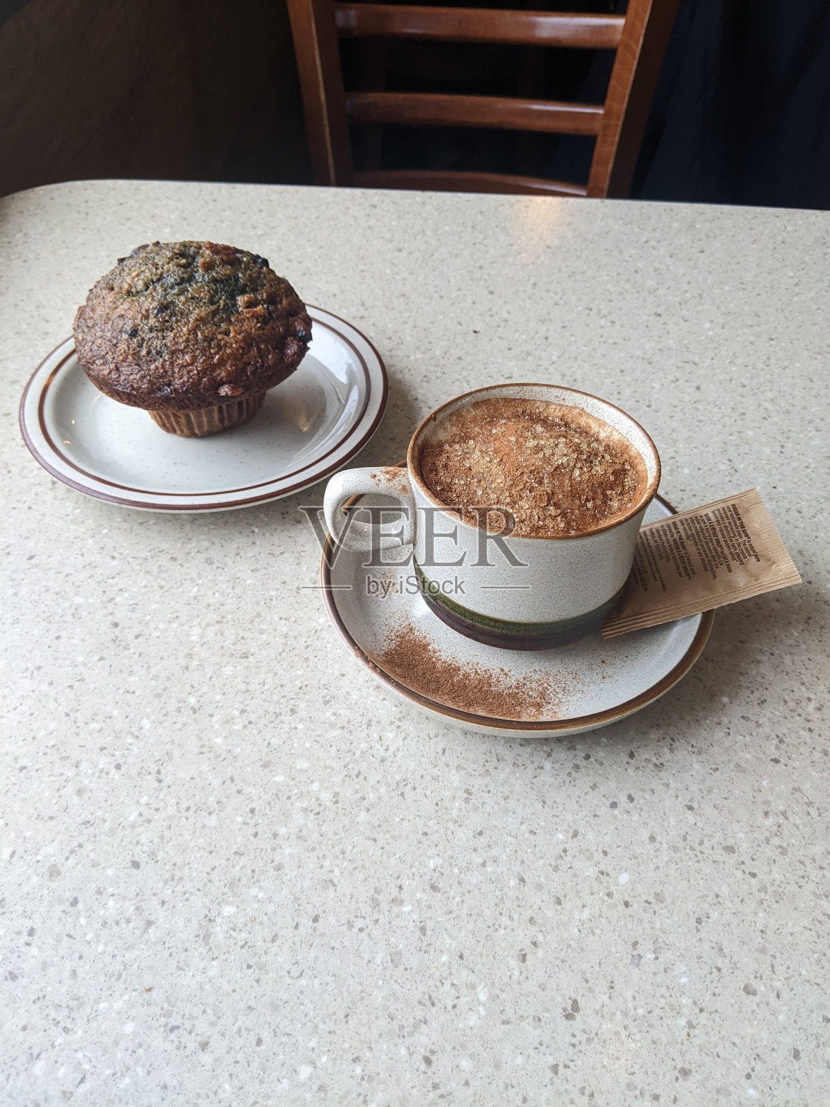 桌上有一杯卡布奇诺和一块松饼照片摄影图片