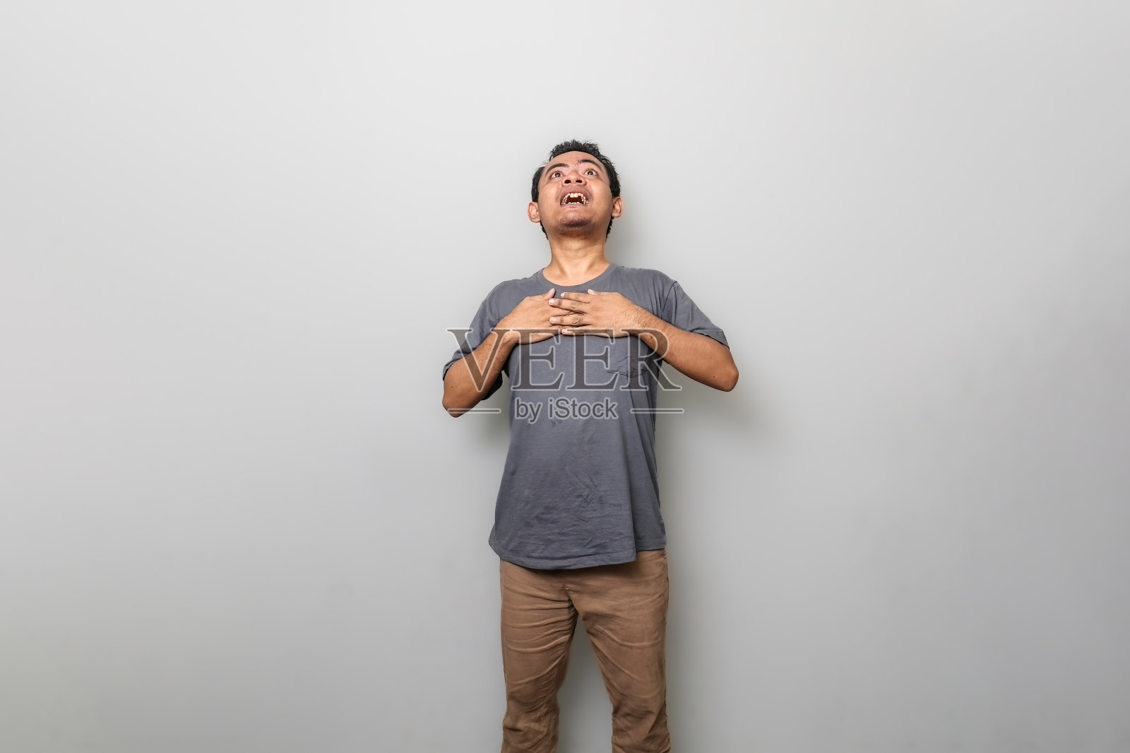 穿灰色衣服的亚洲男人抬起头时感到惊讶或震惊照片摄影图片