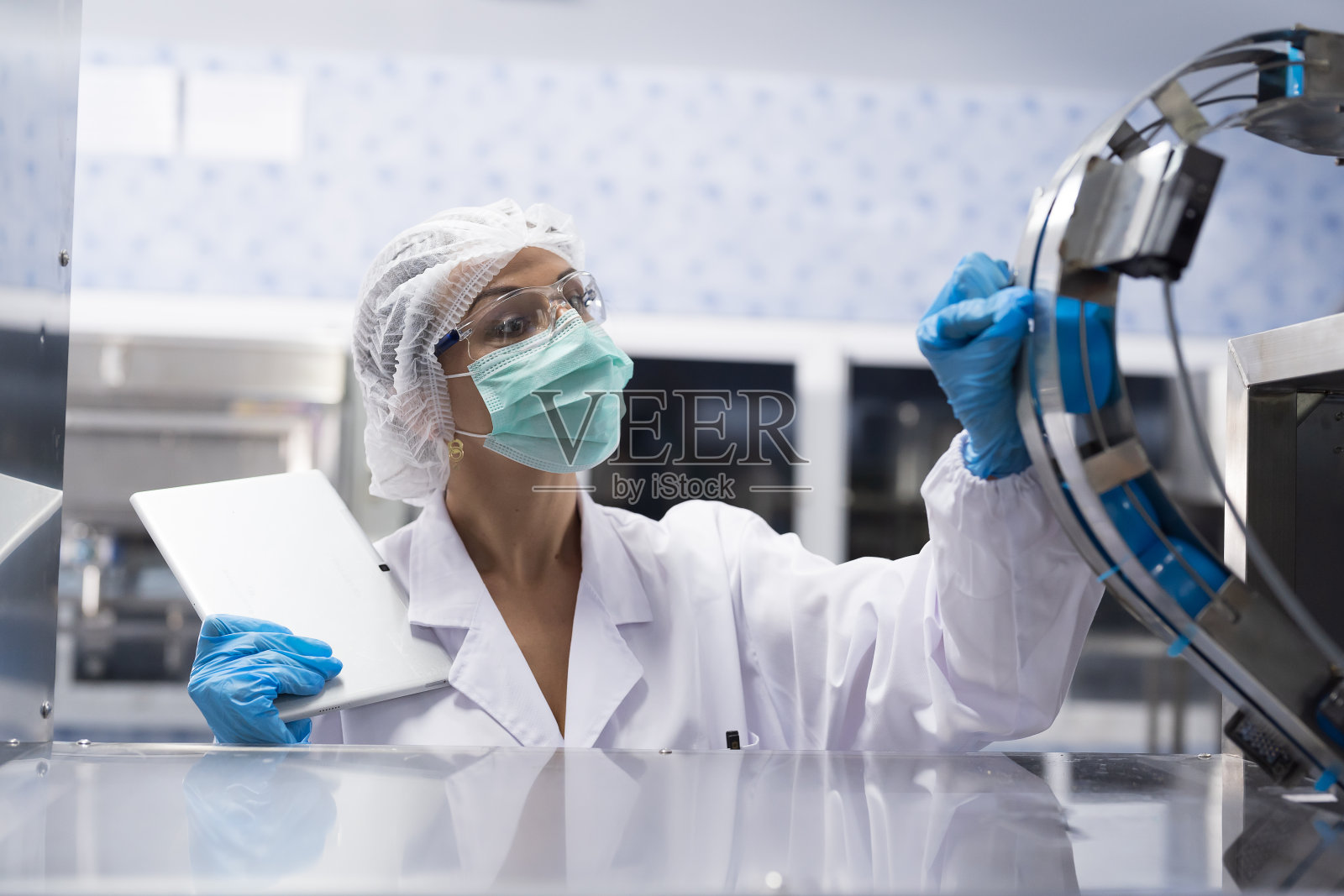 女工在饮水厂生产塑料水箱传送带质量检测。在输送生产线上使用片剂和检查瓶或加仑的工人照片摄影图片