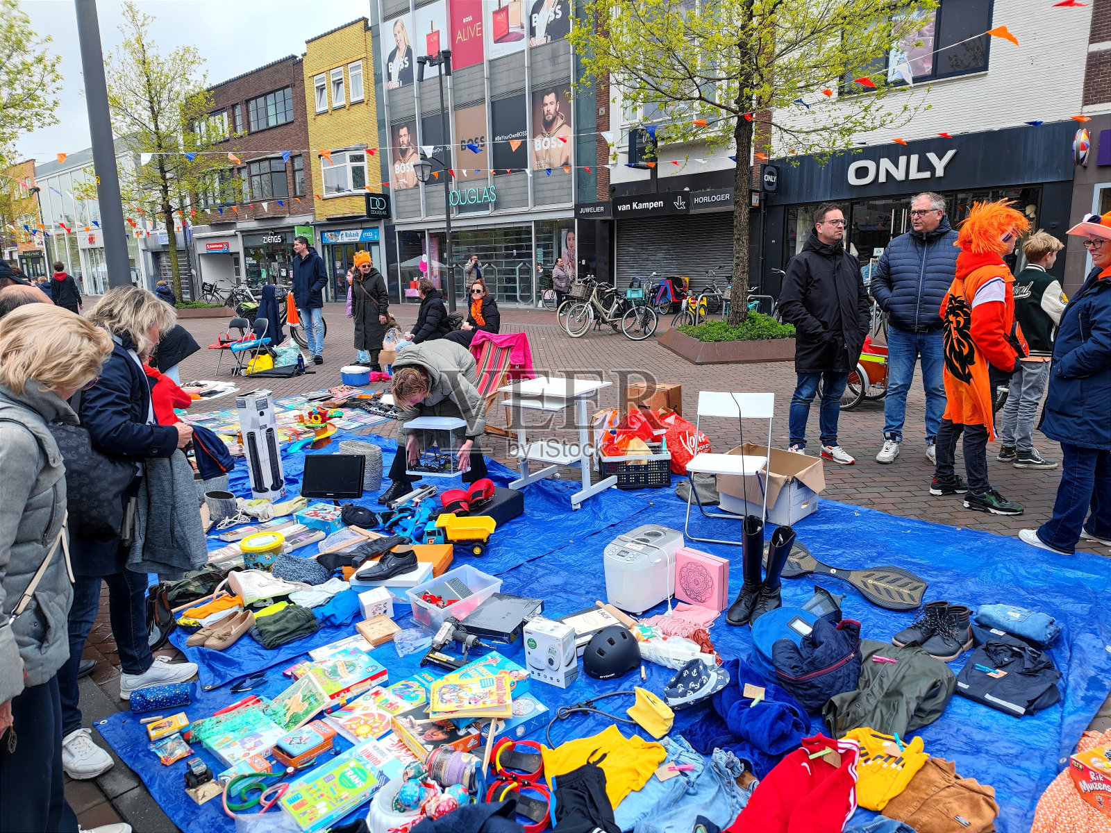 2024年4月27日，荷兰贝弗维克的跳蚤市场上，孩子们和大人穿过街道，在地毯和垫子上买东西，卖东西，庆祝国王节照片摄影图片