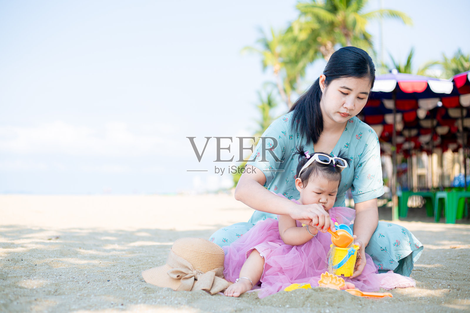 母亲和女孩在沙滩上玩沙子，泰国芭堤雅。母亲和孩子在沙滩上玩沙子照片摄影图片