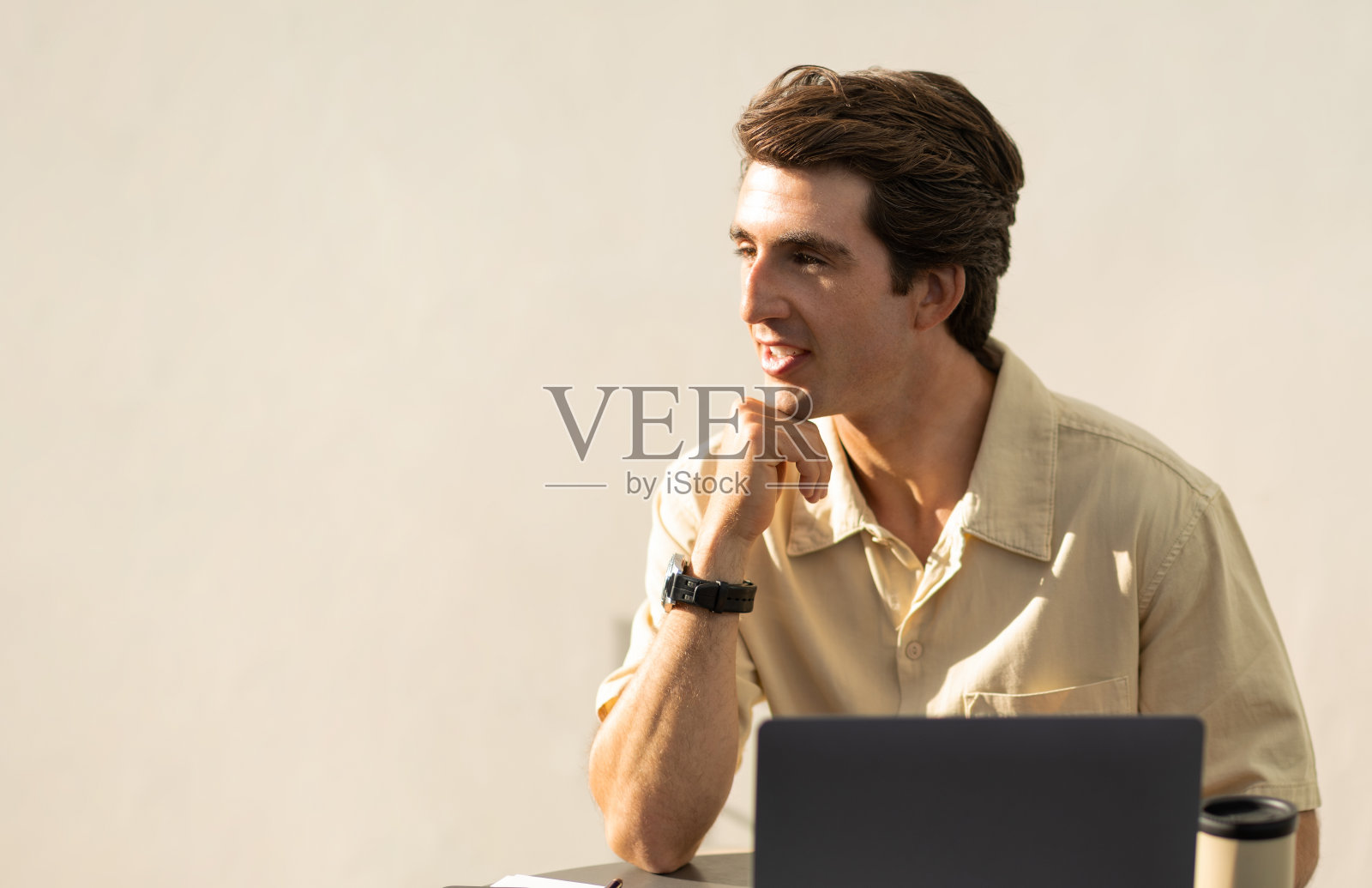 兴致勃勃的年轻商人坐在桌边，用着笔记本电脑照片摄影图片