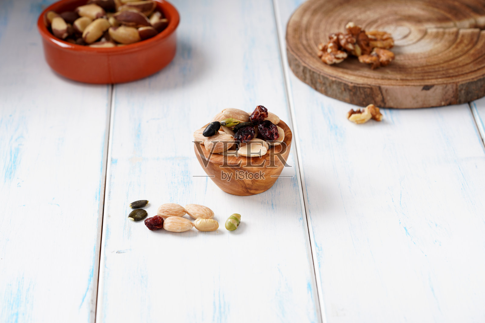各种各样的浆果、坚果和种子放在一个木制的碗里，放在一张木制的桌子上。照片摄影图片