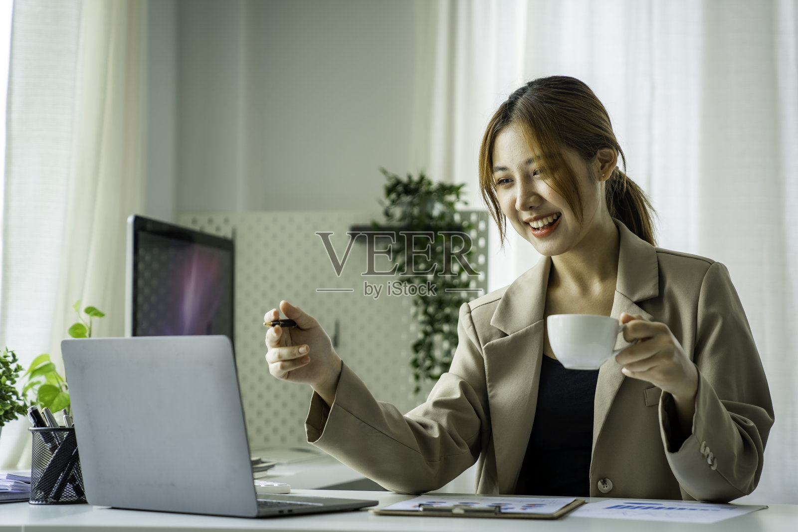 年轻漂亮的亚洲女商人喝着咖啡，用着笔记本电脑照片摄影图片